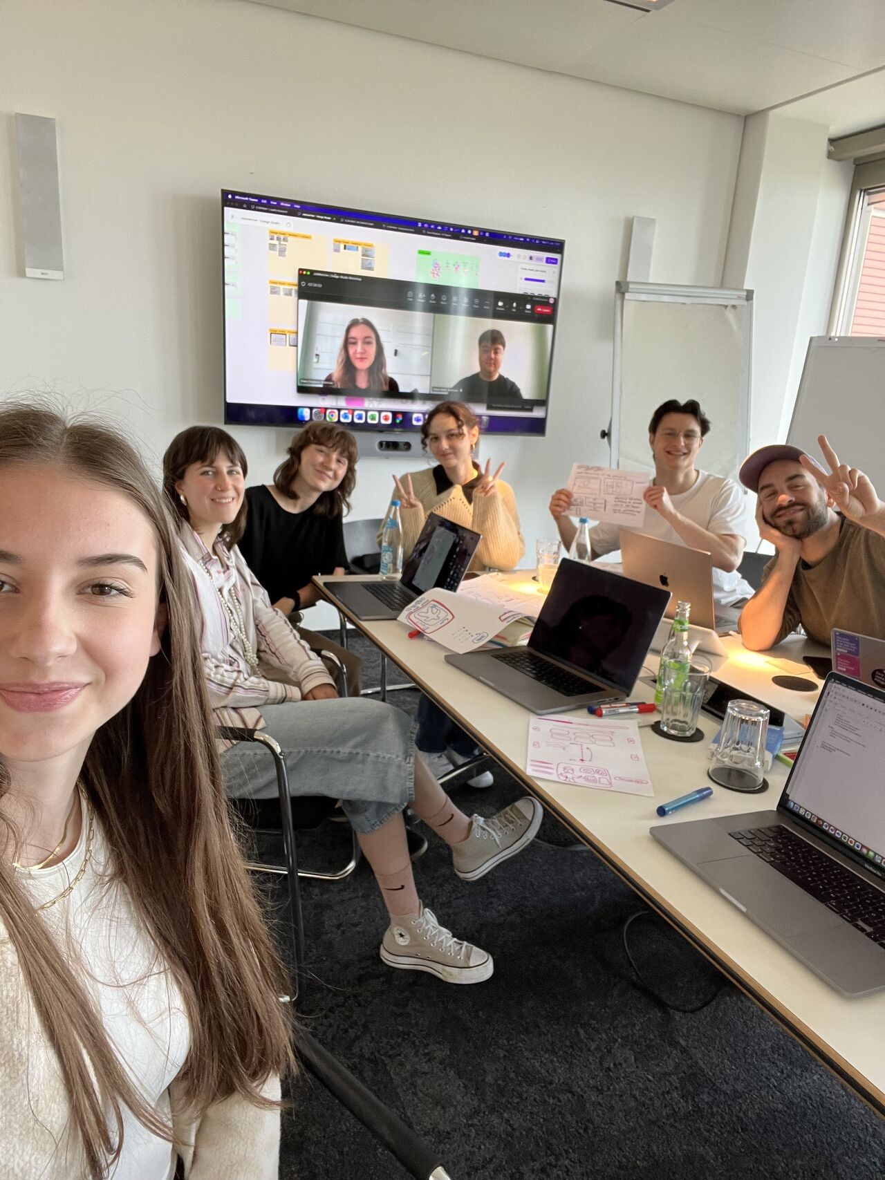 Intern team in the workshop room with remote colleagues on screen
