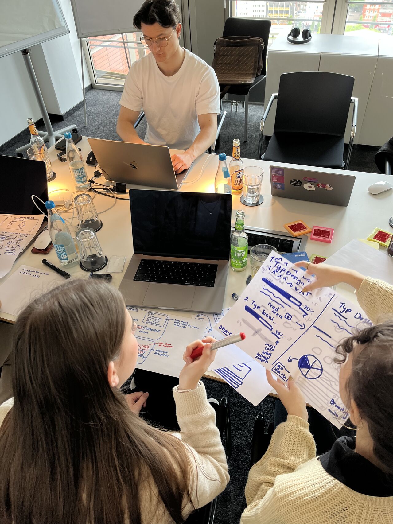 Overhead view of laptops and hand-drawn wireframes on the table